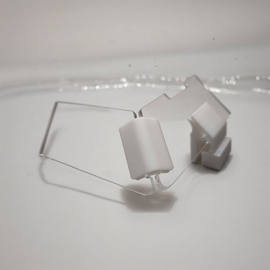 Zwei transparente Aquakallax JumpStop Sprungschutzecken mit weißen Klemmhaltern in schräger Ansicht