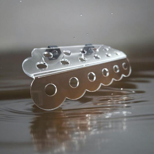 Transparenter Aquakallax ReefDeck für 17 Korallenplugs mit runden Öffnungen und Magnetbefestigung auf reflektierendem Wasserhintergrund