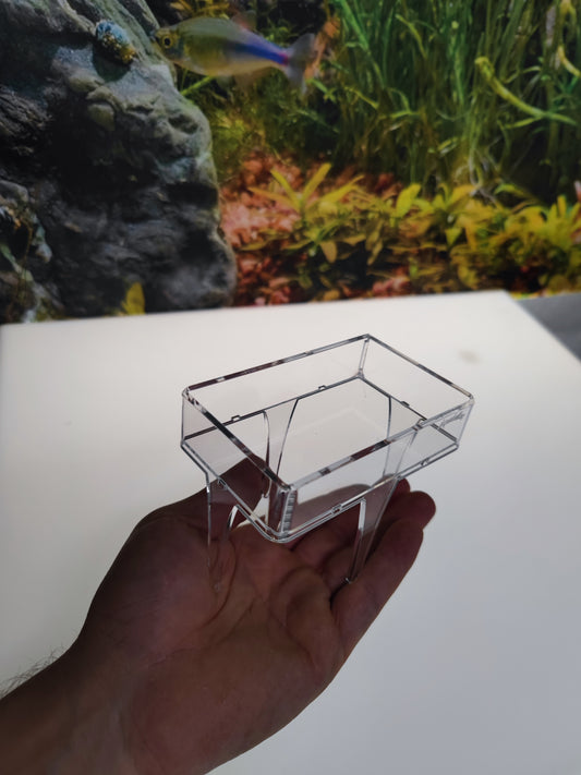 Transparentes Aquakallax Futterpodest mit rechteckiger Schale und Standbeinen in der Hand vor einem Aquarium