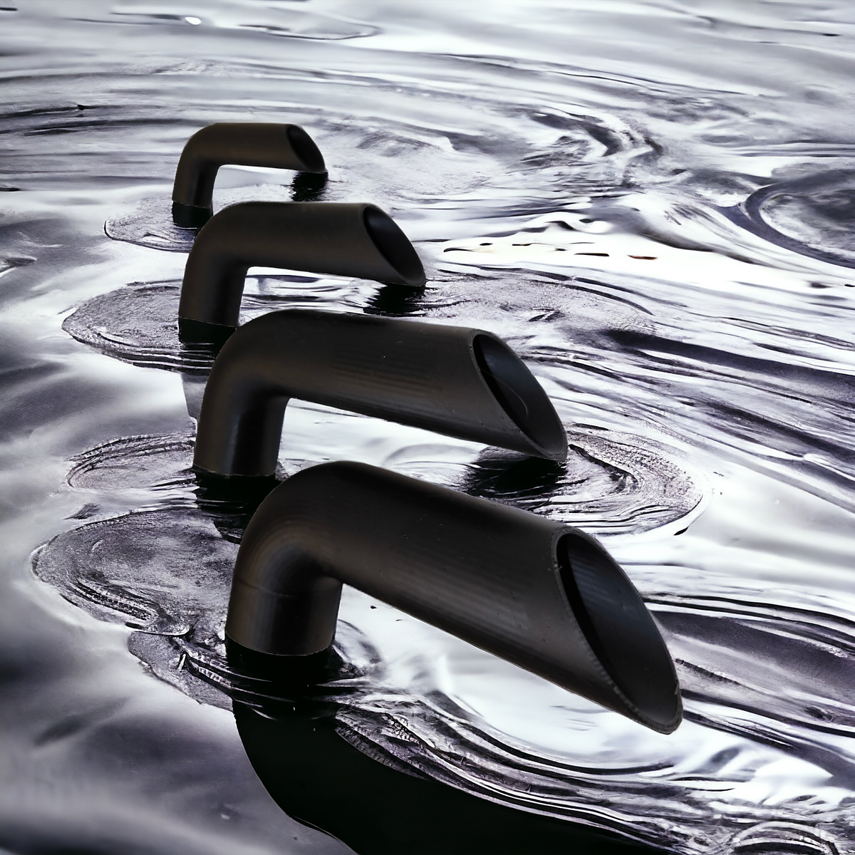Vier schwarze Aquakallax Ausströmerwinkel für Luftheber in unterschiedlichen Größen auf reflektierendem Wasserhintergrund