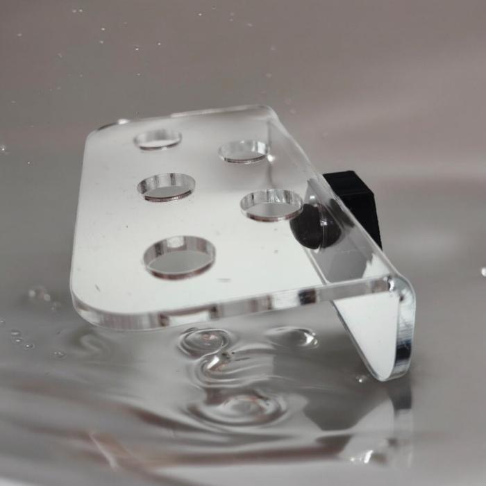 Transparenter Aquakallax ReefDeck für fünf Korallenplugs mit runden Öffnungen und schwarzer Magnetbefestigung in schräger Ansicht