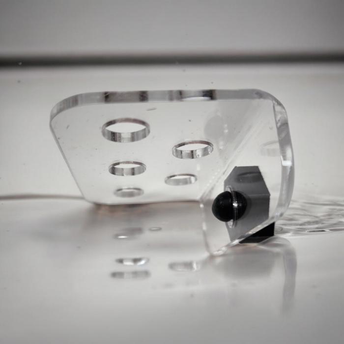 Transparenter Aquakallax ReefDeck für fünf Korallenplugs in der Seitenansicht mit runden Öffnungen und schwarzem Magnethalter