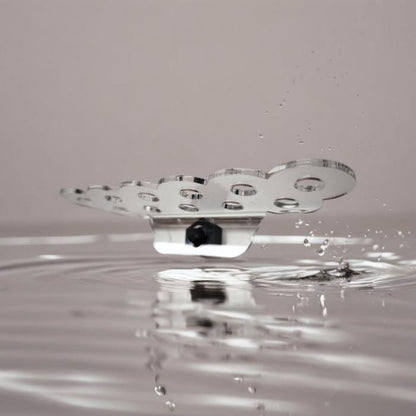 Transparenter Aquakallax ReefDeck für elf Korallenplugs in Bubble-Form mit gewelltem Rand und schwarzem Magnethalter auf Wasserhintergrund